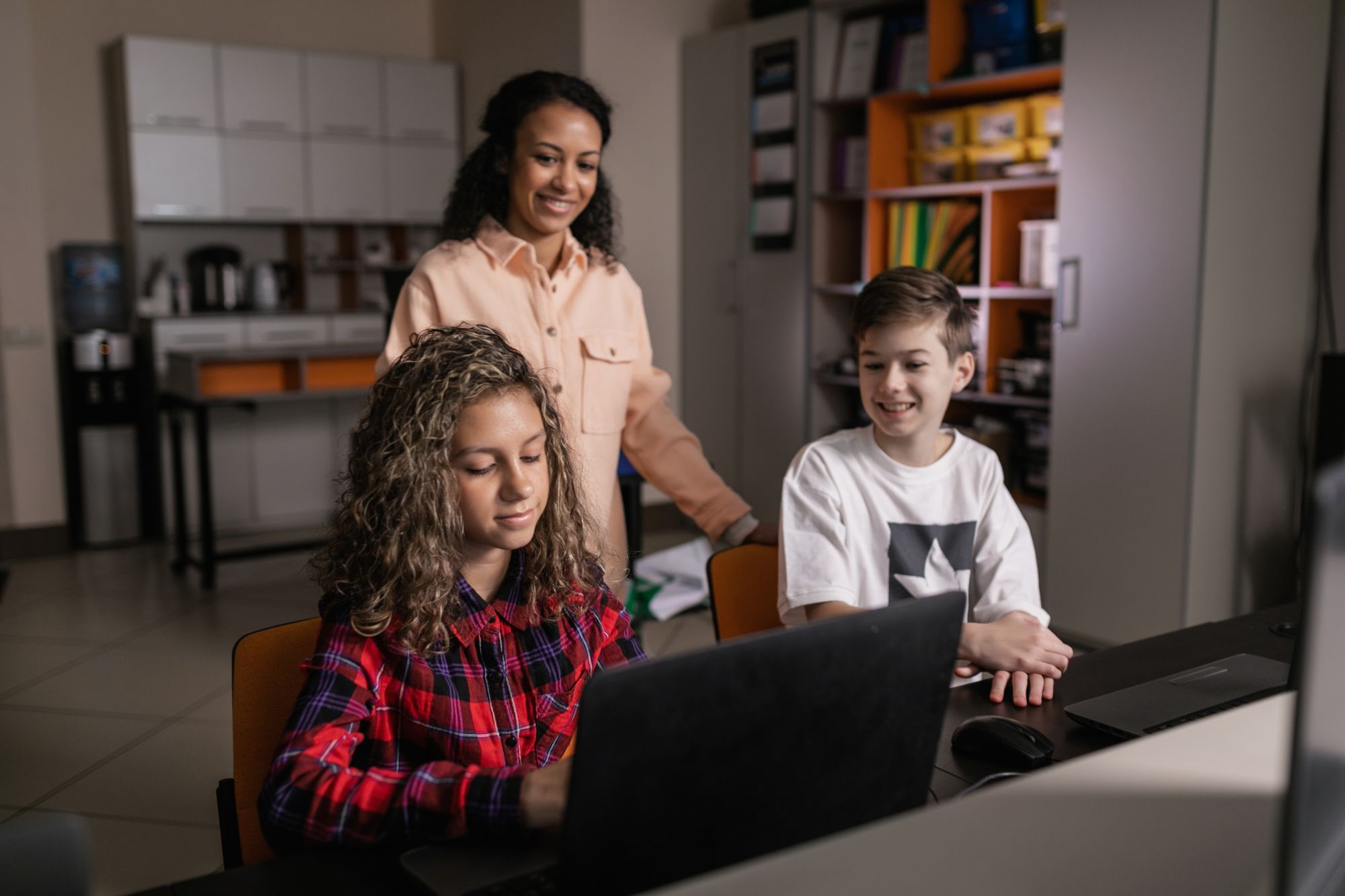 Teacher supporting students working together on a laptop